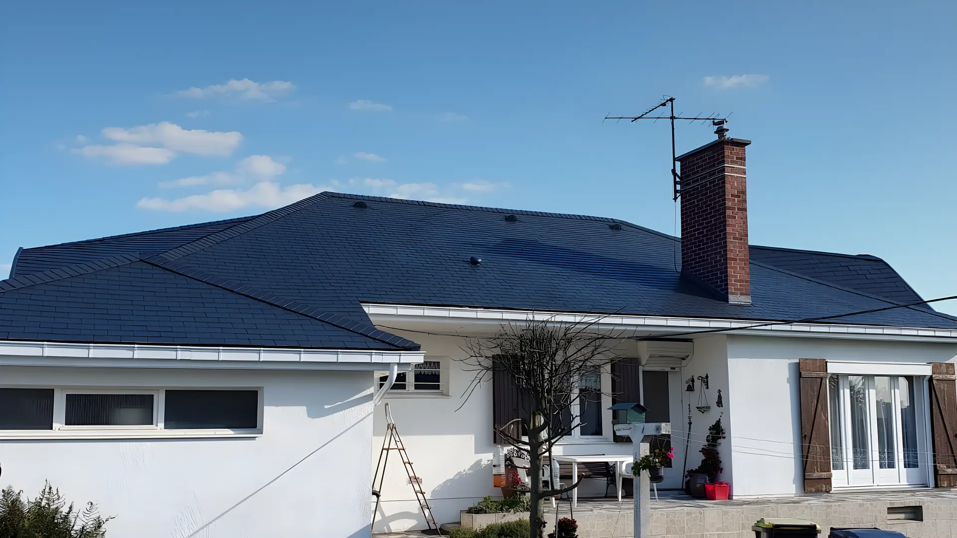 Toiture entièrement refaite en ardoises sur une maison de plain-pied, faîtage et rives terminés, sous un ciel dégagé